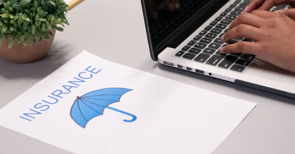 Close-up of hands typing on laptop with an insurance document visible on the desk.